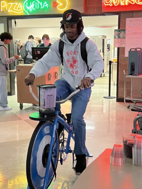 Fort Vancouver ASB student, Tayvon, rides a stationary bicycle to blend smoothies for students during the breakfast meal service.